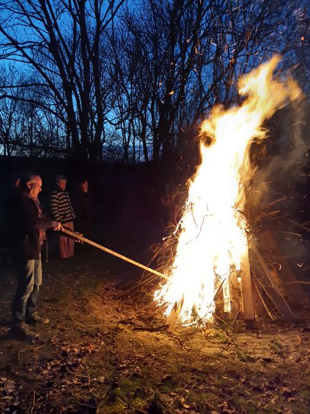 großes Feuer mit 3 Menschen daneben